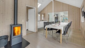 A modern kitchen with a central island, wooden walls, and a dining area with a table and chairs.