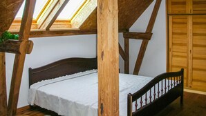 A loft bedroom with a sloped ceiling, wooden beams, a bed, and a skylight. - Cozy home in Nowe Warpno with ethernet internet (Nowe Warpno)