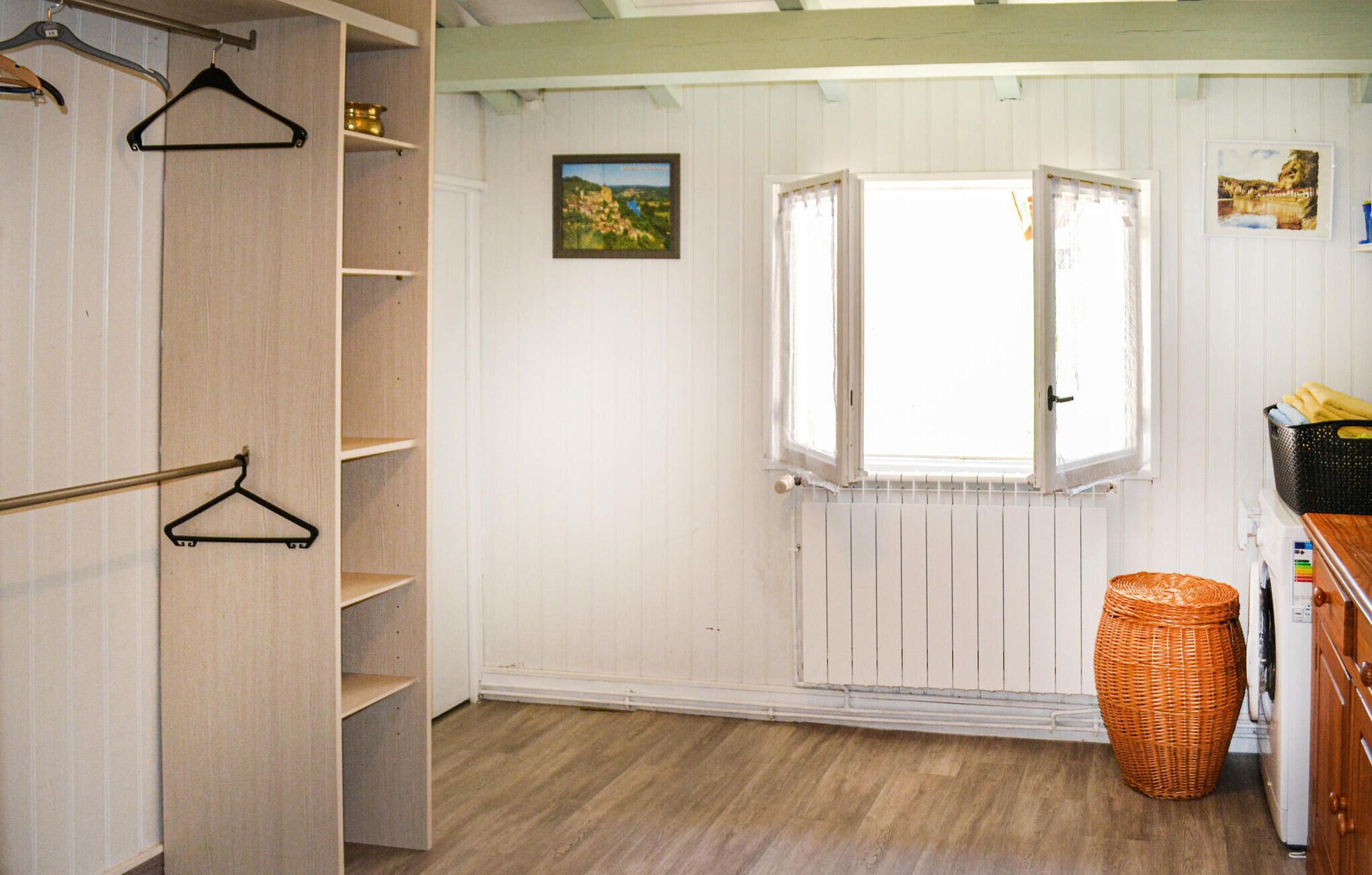 A room with a wooden floor, a window with white shutters, a radiator, and a basket.