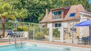 Il s’agit d’une propriété résidentielle dotée d’une piscine, d’un jardin clôturé et d’une maison avec un toit en tuiles.