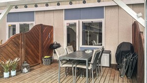 Un patio techado al aire libre con mesa y sillas, una parrilla y una zona de estar cubierta.