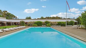 Una piscina rectangular con una asta de banderas al fondo.