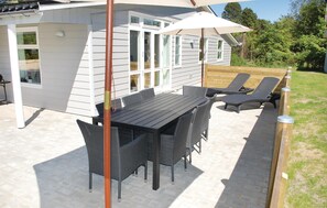 Eine Terrassenanlage im Freien mit Tisch, Stühlen, Sonnenschirm und Holzdeck.