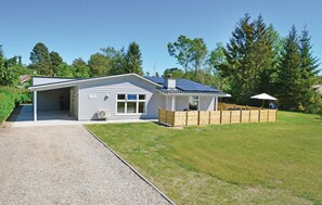 Einbungalow mit Garage, überdachter Veranda und einem eingezäunten Garten.