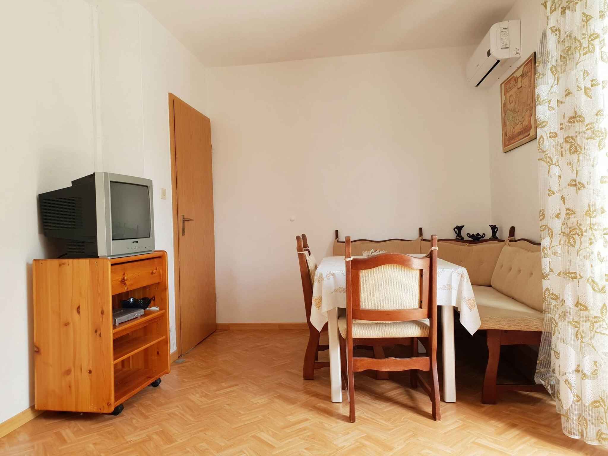 Una stanza piccola e accogliente con un mobile TV in legno, un tavolo con due sedie e un divano.