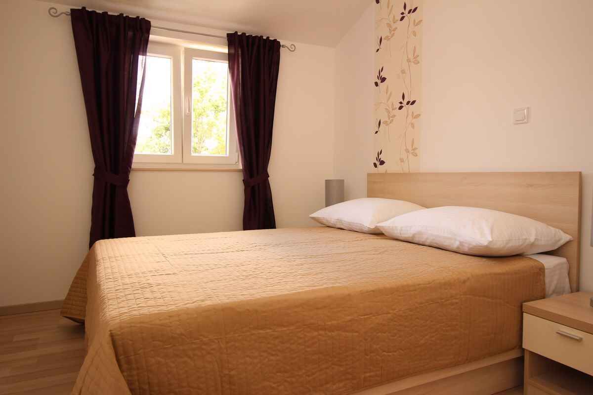 A bedroom with a bed, curtains, a window, and a wall with a floral pattern.