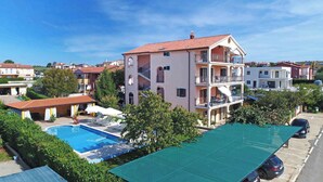 A multi-story building with a swimming pool and outdoor seating area. - Studio with pool and air conditioning (Novigrad)