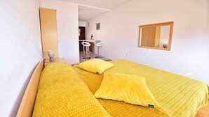 A room with a bed, two yellow pillows, a wooden headboard, a mirror, and a small desk with a chair. - Studio with pool and air conditioning (Novigrad)