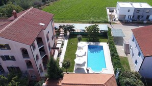 A residential building with a swimming pool, a tennis court, and a green field in the background. - Studio with pool and air conditioning (Novigrad)