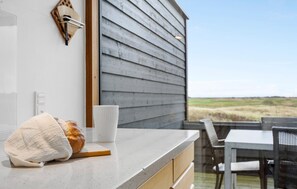 A kitchen counter with a loaf of bread, a white cup, and a wooden cutting board. - Lovely home in Rømø with sauna (Rømø)
