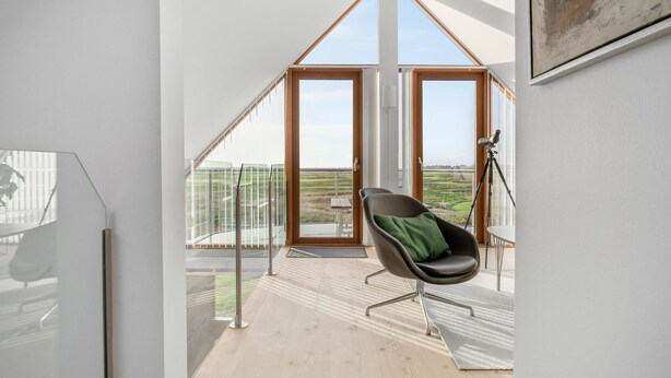 Ein modernes Zimmer mit einem großen Fenster, einem Sessel und einem Teleskop.