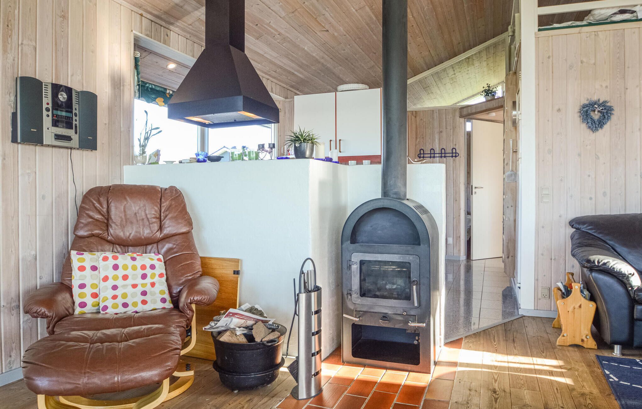 Ein gemütliches Wohnzimmer mit Ledersessel, Kamin und Holzeinrichtung.