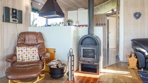 A cozy living room with a leather armchair, a fireplace, and a wooden interior. - Awesome home in Hejls with sauna (Hejls)