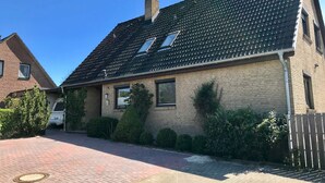 Ein eingeschossiges Haus mit Ziegeldach, Backsteinmauern und einem gepflasterten Auffahrt.