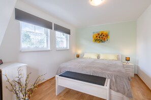 A bedroom with a bed, bedside tables, a bench, a window, and a painting.
