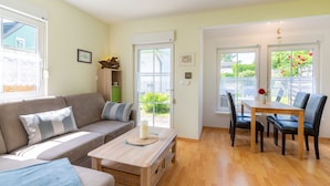Een moderne woonkamer met een bank, een salontafel en een eethoek met een tafel en stoelen.