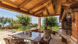 Eine Terrasse im Freien mit einem Steintisch, Stühlen und einem Backofen aus Ziegeln.