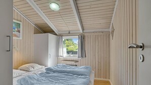 Une chambre avec deux lits, des murs en bois, un ventilateur de plafond et une fenêtre avec des rideaux.