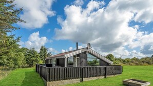 Une maison moderne avec un toit en pente, de grandes fenêtres et une terrasse en bois.
