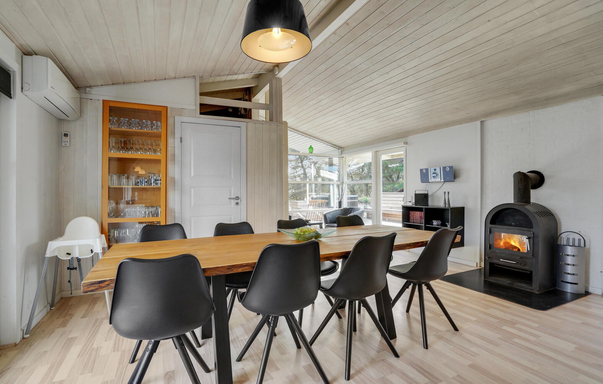Een moderne eetruimte met een houten tafel, zwarte stoelen en een ingebouwde open haard.