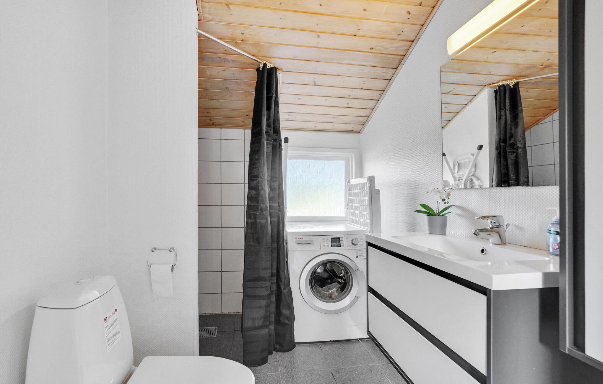 Ein kleines, modernes Badezimmer mit Waschmaschine, Waschbecken und Toilette.