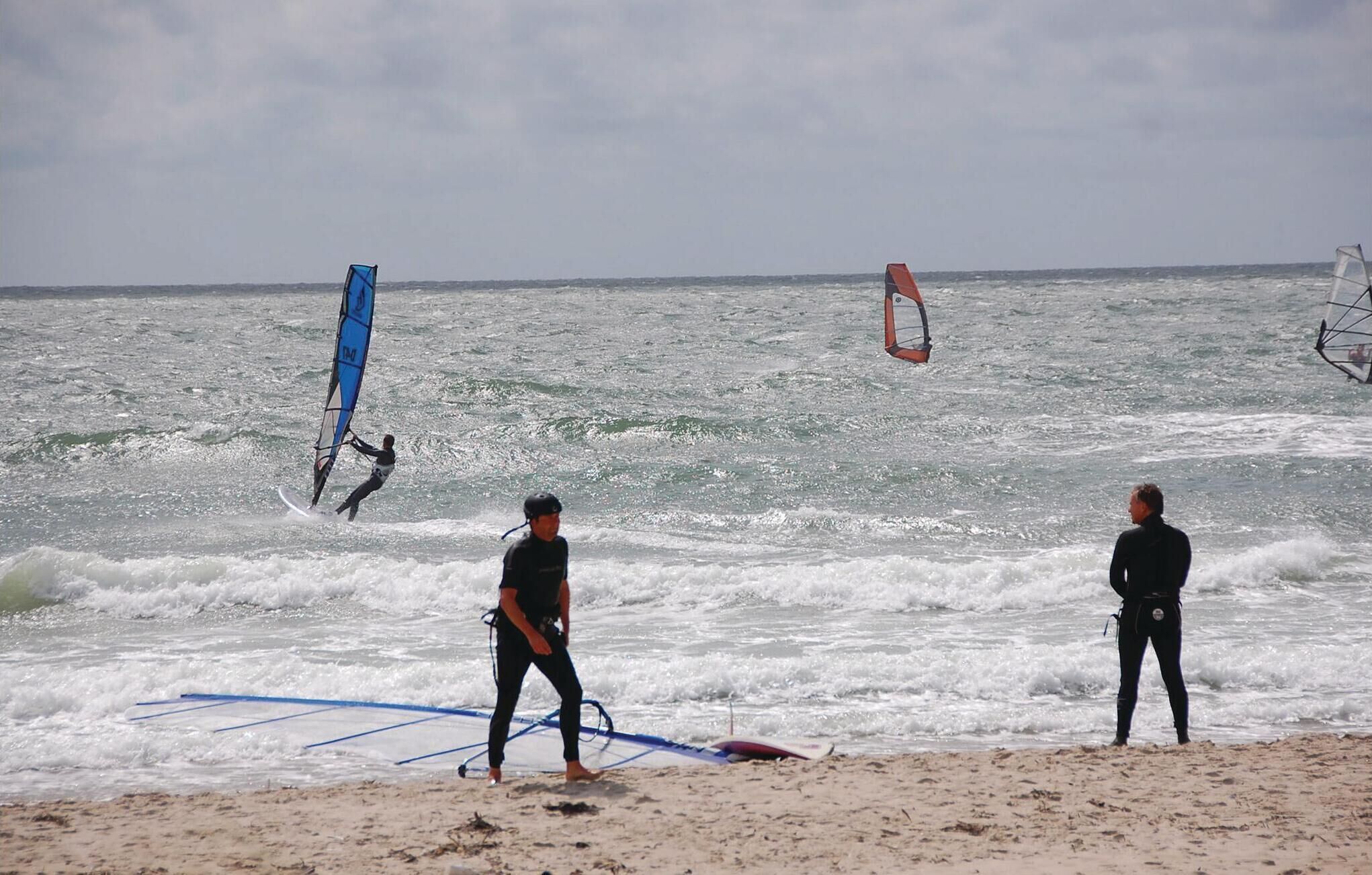 Una spiaggia con persone e attrezzatura per windsurf.
