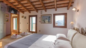 Ein Schlafzimmer mit Bett, Schreibtisch, Stuhl, Fernseher und einem Fenster mit Bergblick.