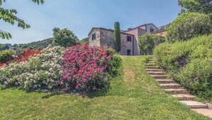 Ein Steinhaus mit einem Gartenweg, der zu einer Treppe führt.