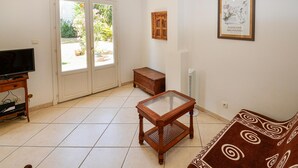 Una sala de estar con televisor, una mesa de madera, un sofá y un cuadro en la pared.