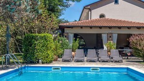 A swimming pool with lounge chairs and a covered patio area.