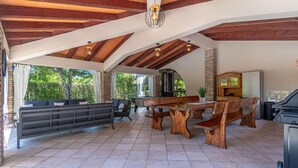 A spacious patio area with a wooden table and benches, a sofa, and a cabinet.