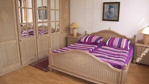 A bedroom with a bed, a wardrobe, and a nightstand.