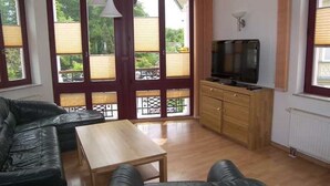 A room with a wooden cabinet, a leather sofa, a wooden table, and a TV.