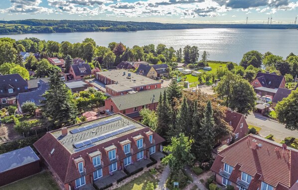 Luchtbeeld van een woongebied met huizen, zonnepanelen op daken en een meer op de achtergrond.