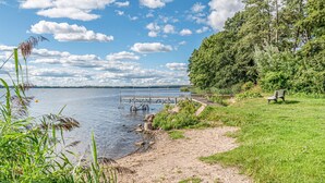 Un parc au bord du lac, avec une jetée en bois, une pelouse et un banc.