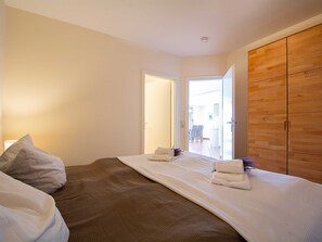 A bedroom with a bed, a wooden wardrobe, and a door leading to a balcony. - MB. 4 17 - Ocean View Apt. MB-417 .. (Kühlungsborn)