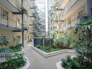 A multi-level atrium with a central garden, balconies, and a glass ceiling.
