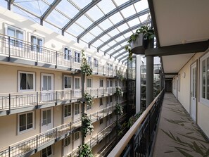 Un atrium à plusieurs niveaux, doté de balcons, de grandes fenêtres et de plantes suspendues.