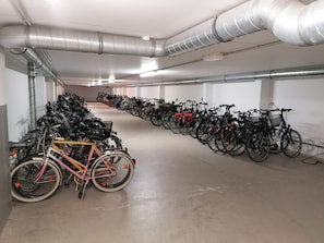 A long, empty indoor parking area with rows of bicycles and scooters.