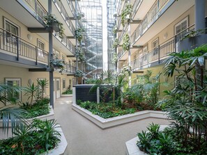 A multi-level atrium with a central garden, balconies, and a glass ceiling.