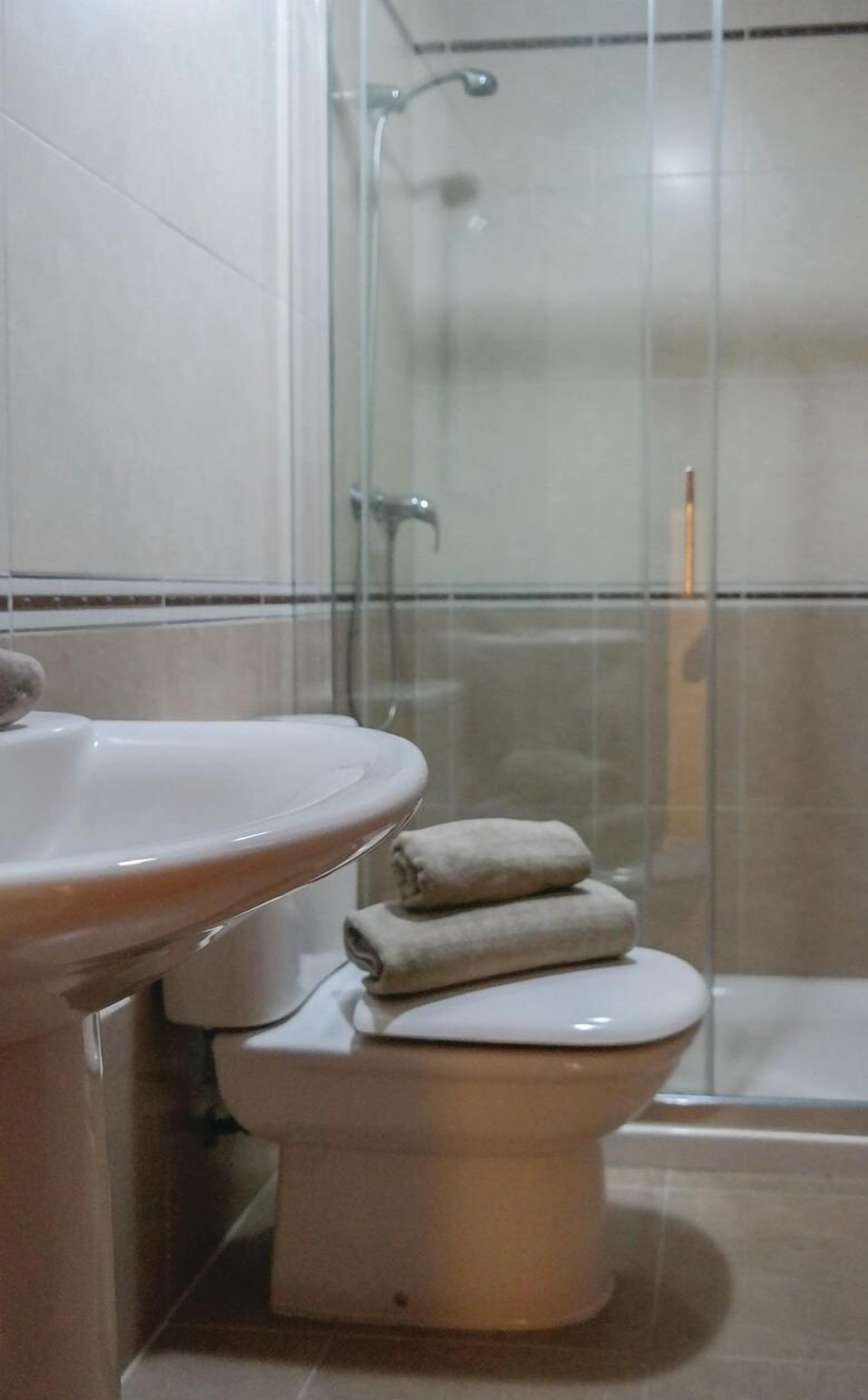 Un baño con lavamanos, inodoro y cabina de ducha de vidrio.