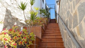 Una scala con gradini in terracotta che conduce a un edificio con pareti in pietra e un cancello in metallo.