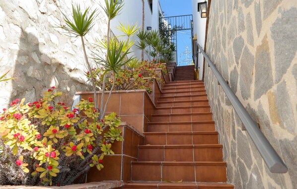 Una escalera con escalones de terracota que conduce a un edificio con paredes de piedra y una puerta de metal.