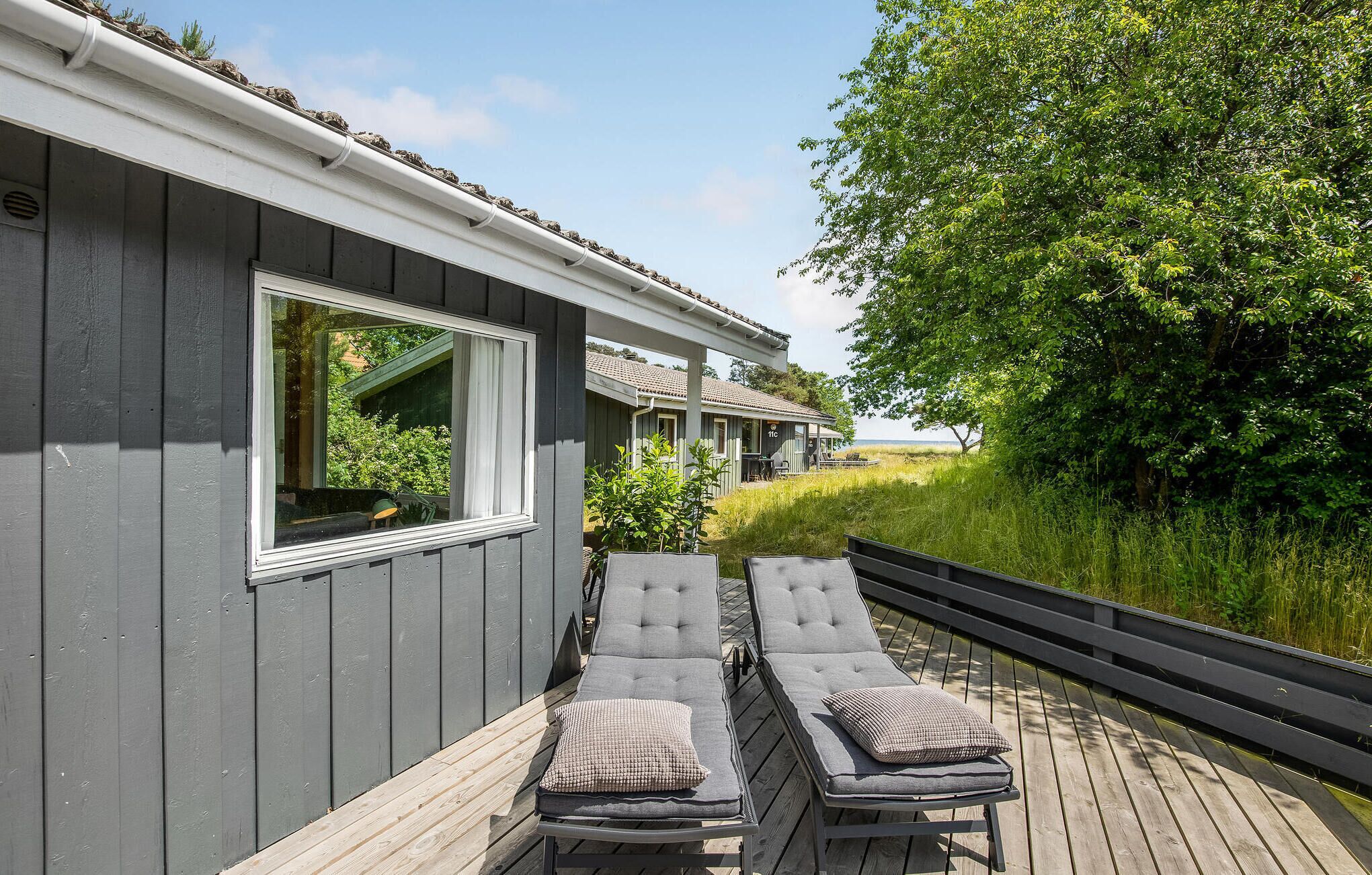 A wooden deck with two sun loungers and a window overlooking a grassy area.