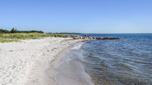A sandy beach with clear water, a rocky breakwater, and distant trees. - Nice home in Rudkøbing with WiFi (Rudkøbing)