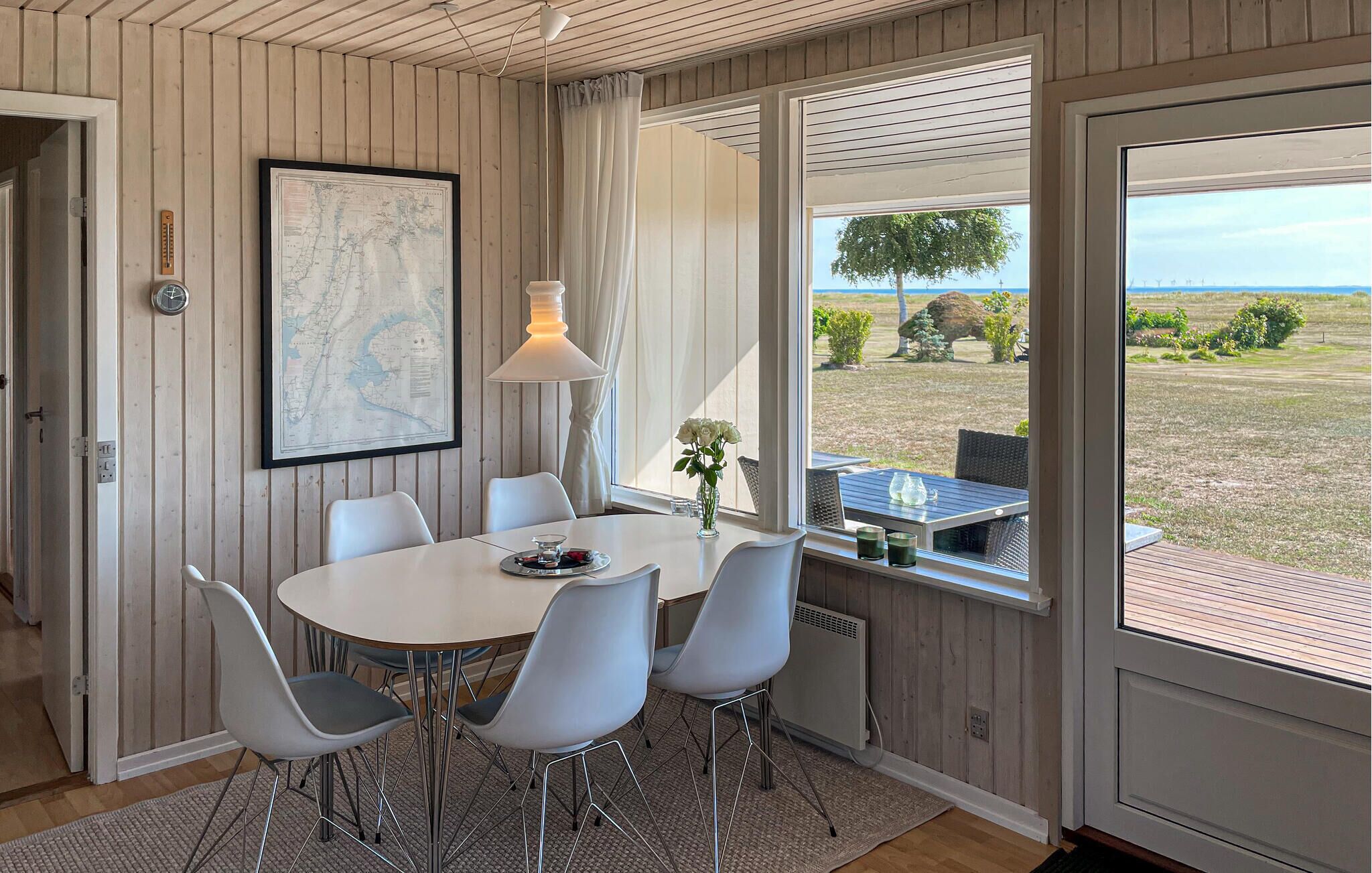 A dining area with a round table, four chairs, a map on the wall, and a view of the outdoors.