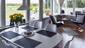 A dining area with a white table, black placemats, and white chairs. There is a vase with yellow flowers on the table. - Nice home in Rudkøbing with WiFi (Rudkøbing)