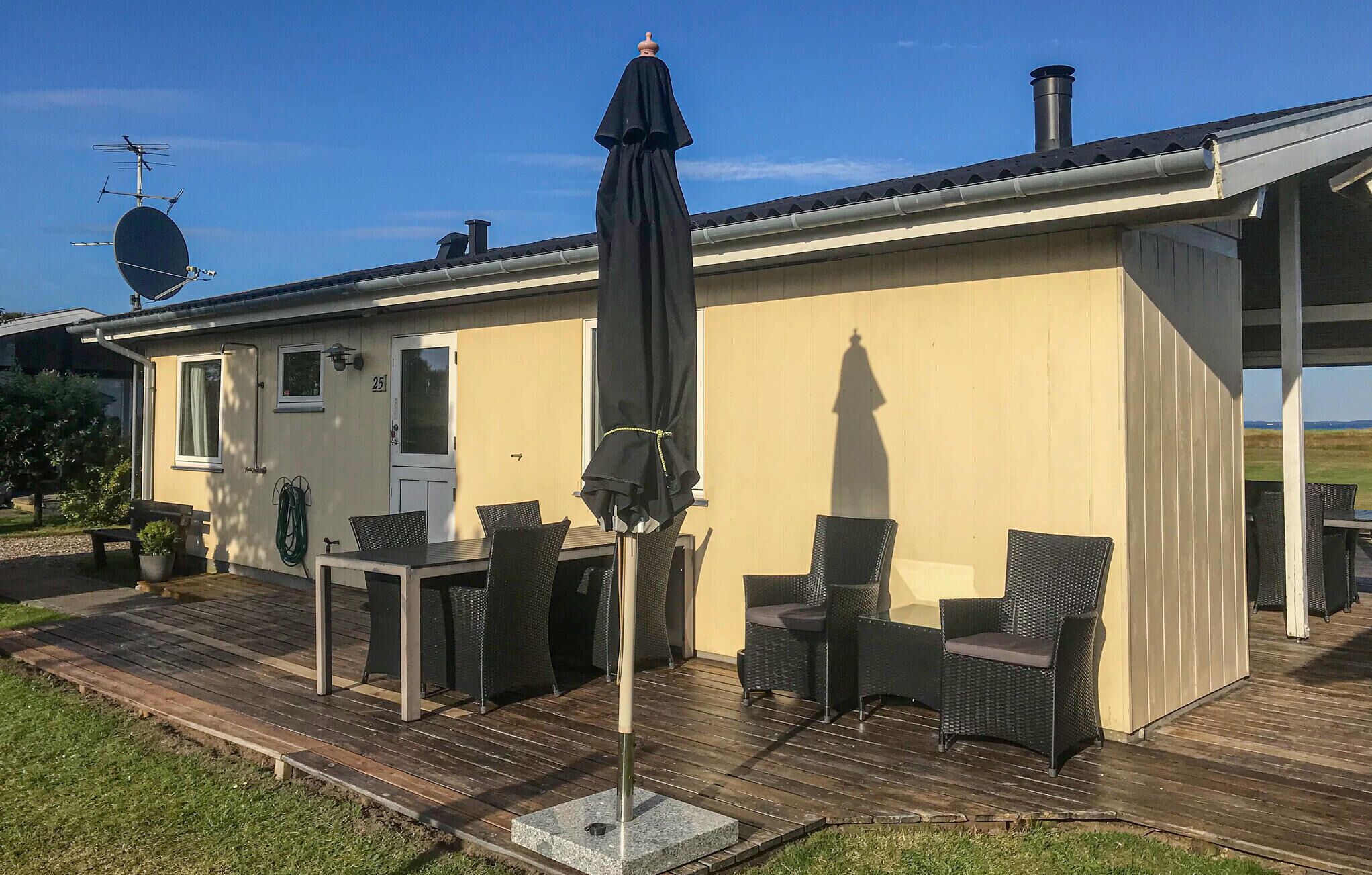 Une maison dotée d’un patio comprenant une table et des chaises, une antenne parabolique et une cheminée.