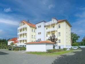 Un edificio residenziale a più piani con balconi, un ingresso coperto e un vialetto lastricato.