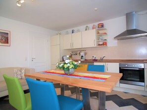Une cuisine compacte comprenant une table à manger, des chaises, une machine à café et une cuisinière.